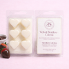 Packaged heart-shaped wax melts with a visible brand logo on a pink background